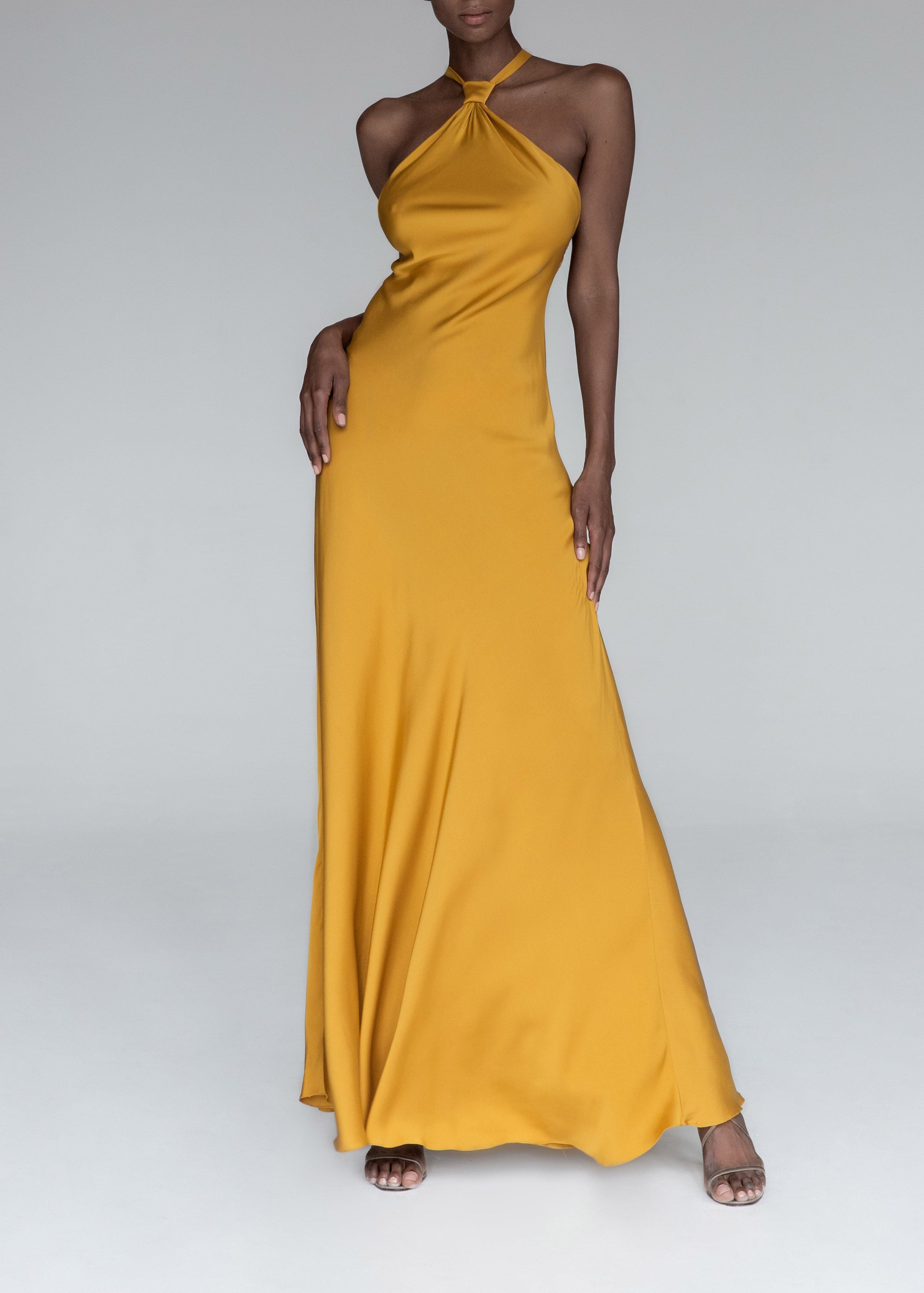 Model wears yellow silk halterneck evening dress