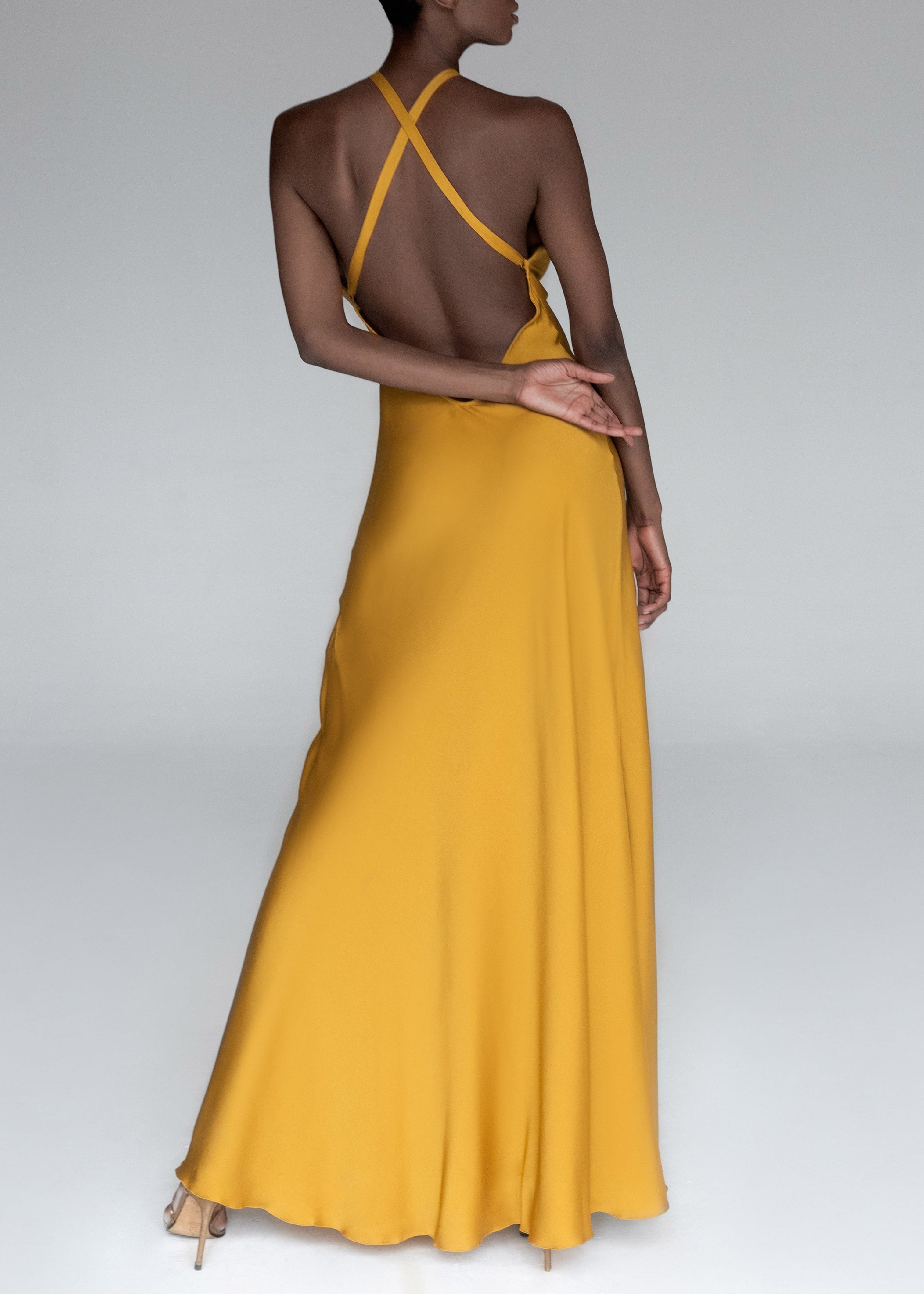 Model wears yellow silk halteneck evening dress
