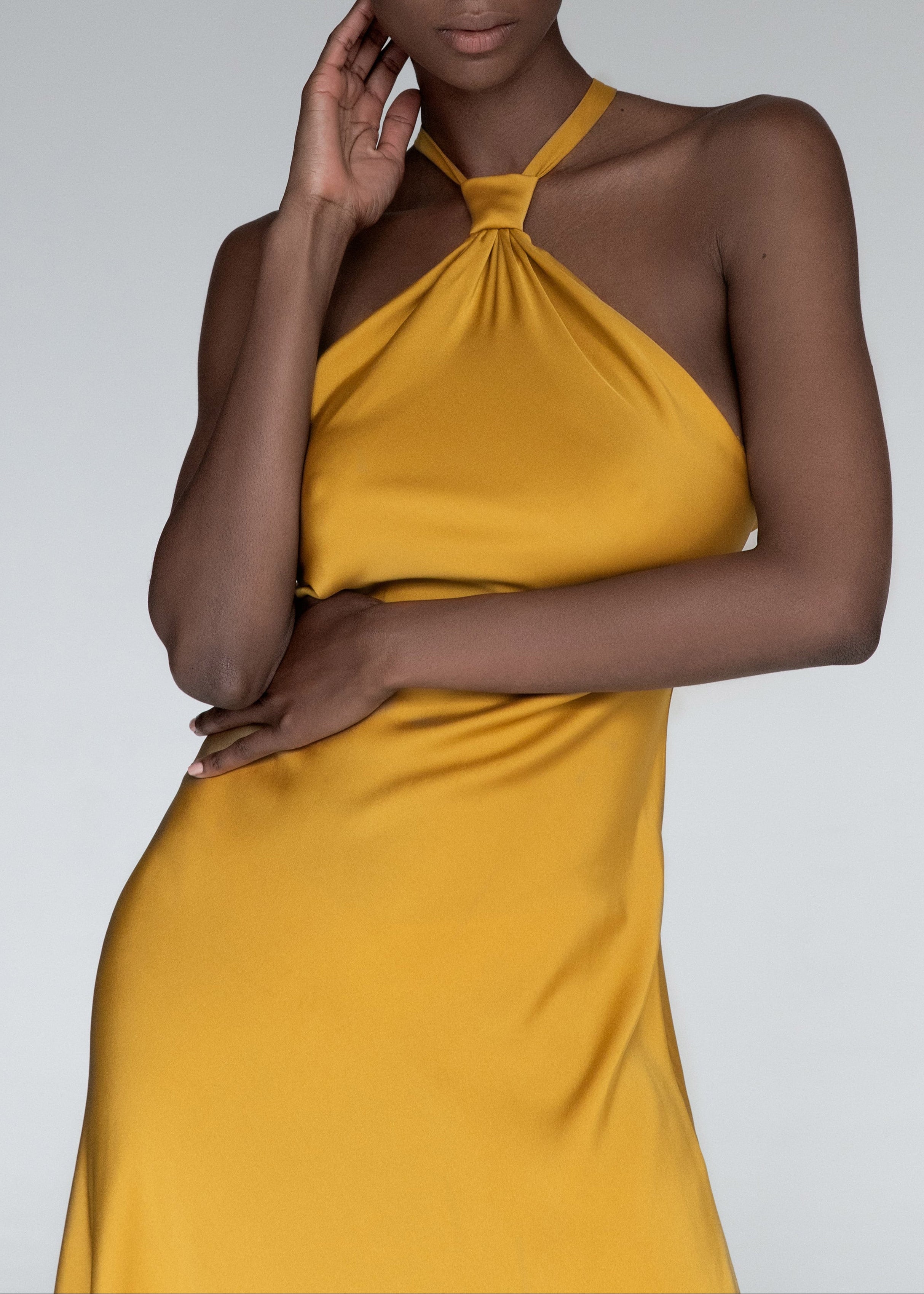 Model wears yellow silk halteneck evening dress